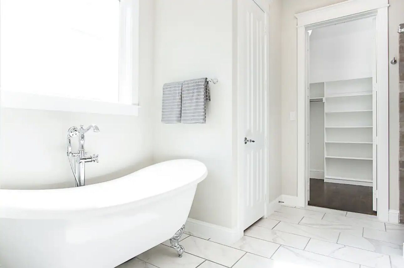 A bathroom with a freestanding bathtub, a towel rack, and a walk-in closet with shelves.