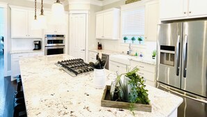 Una cocina moderna con armarios blancos, electrodomésticos de acero inoxidable y una isla de mármol.