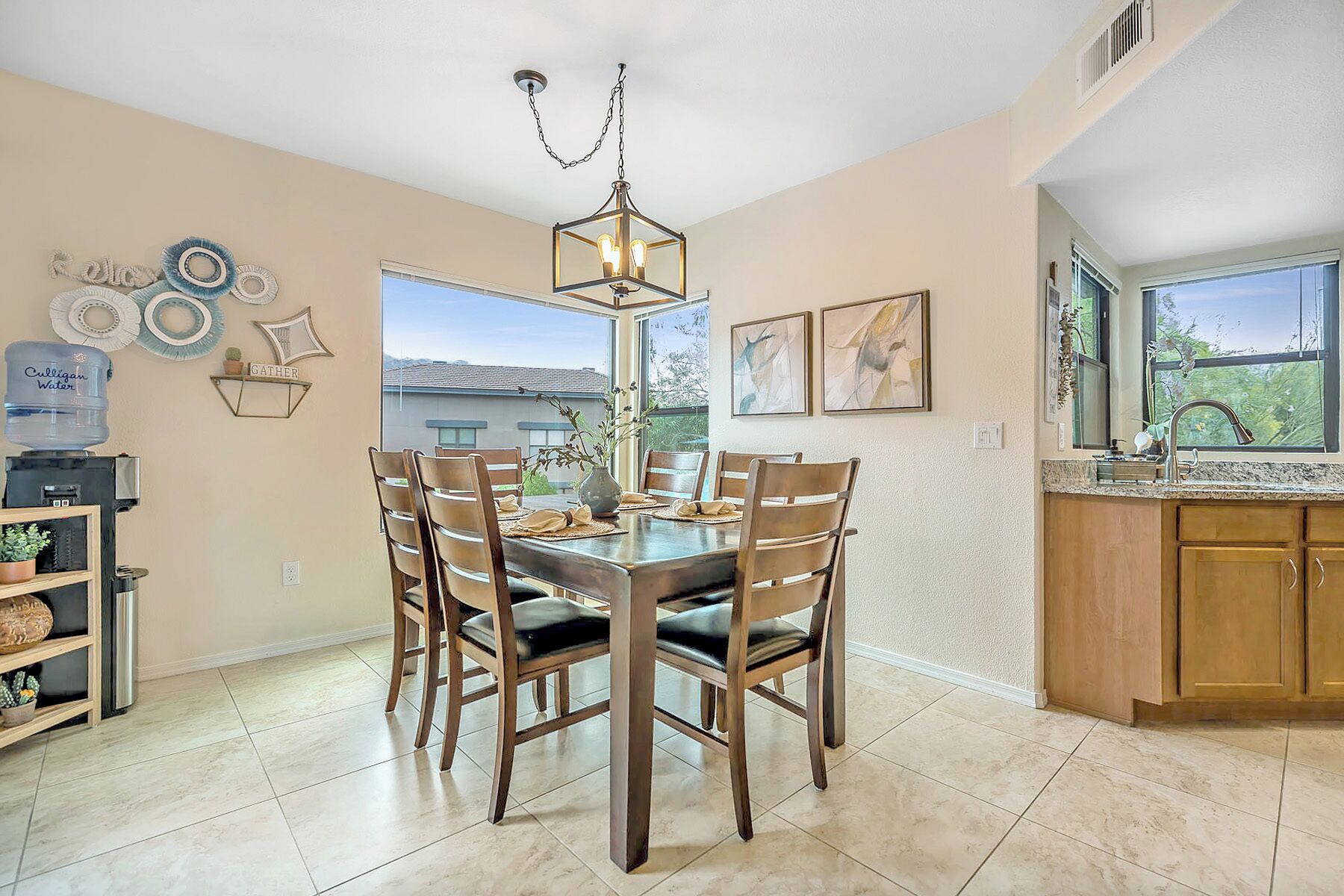 A dining area with a wooden table and chairs, a water dispenser, and a chandelier.