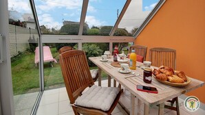 A dining area with a table set for breakfast, including bread, juice, and tea. - Les Bancs Roux - Binic Etables SUR MER (BINIC ETABLES SUR MER)