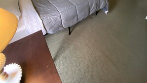 A bedroom with a bed, a dresser, a mirror, and a nightstand with a lamp.
