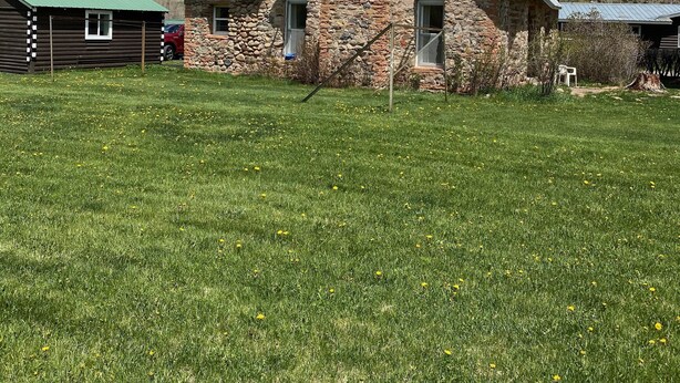 A stone house with a green roof, satellite dishes, and a chimney.