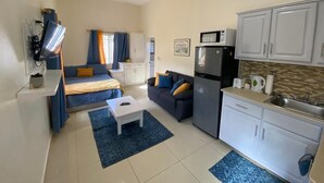 A compact living space with a kitchenette, a sofa, a coffee table, and a ceiling fan. - Cozy Studio Apartment in Quiet Neighborhood (Philipsburg)