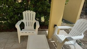 A patio area with two white plastic chairs and a small table. - Cozy Studio Apartment in Quiet Neighborhood (Philipsburg)