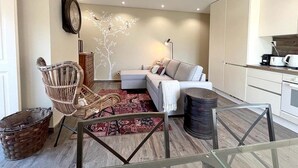 A modern living room with a sofa, a wicker chair, a coffee table, and a decorative wall piece. - Eighteen21 Houses - Casa da Mula in Quinta Velha (Sintra)