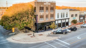 A street view with a building labeled "HUPFORD" and another building with a sign for "Ardmore Finance." There are cars parked on the street and a bicycle lane. - Deluxe Studio in Historic Downtown Building! (Bartlesville)