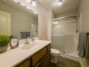 Un baño moderno con ducha de vidrio, lavamanos blanco y retrete.