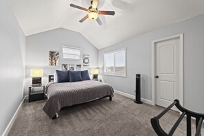 A bedroom with a bed, nightstands, a ceiling fan, and a door.