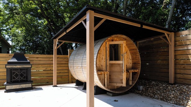 Een houten constructie met dak, een open haard en een houten hek op de achtergrond.