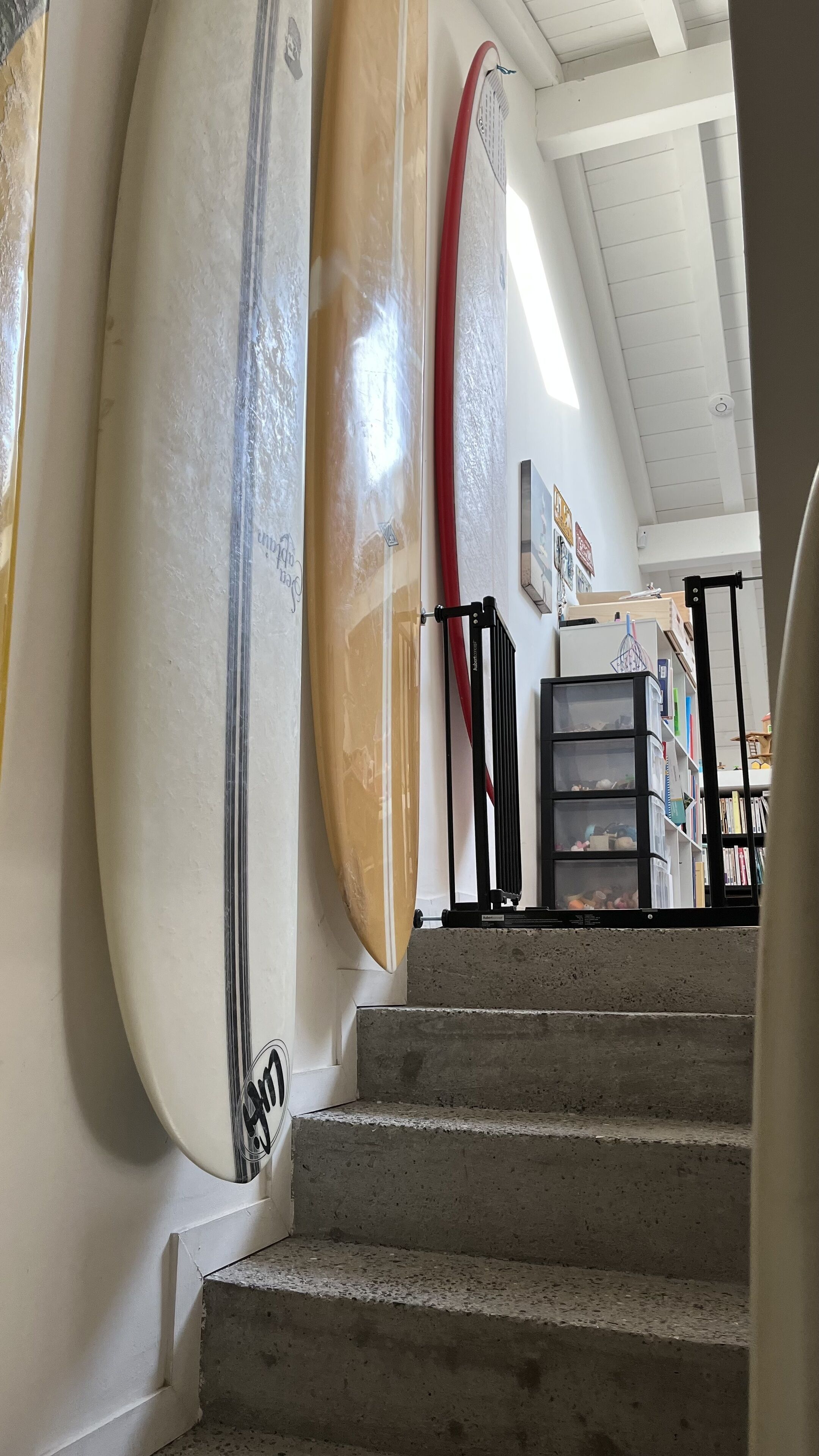 Un escalier menant à une pièce où des planches de surf sont accrochées au mur.