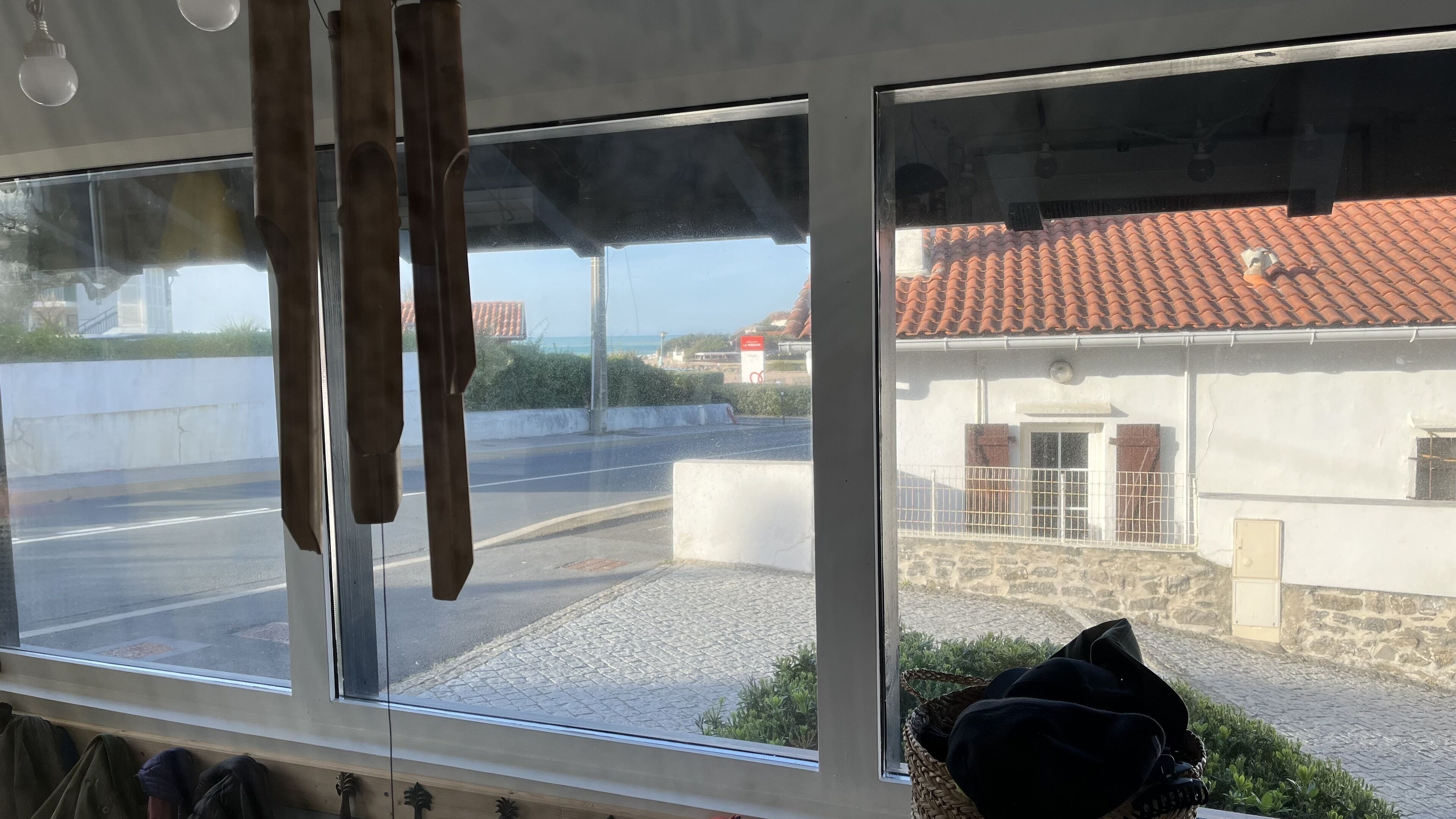 Ett rum med ett stort fönster som vetter ut mot en gata och en byggnad med ett tak täckt av tegelpannor.
