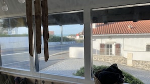 A room with a large window overlooking a street and a building with a tiled roof. - RESIDENCE DE LA PLAGE (Bidart)