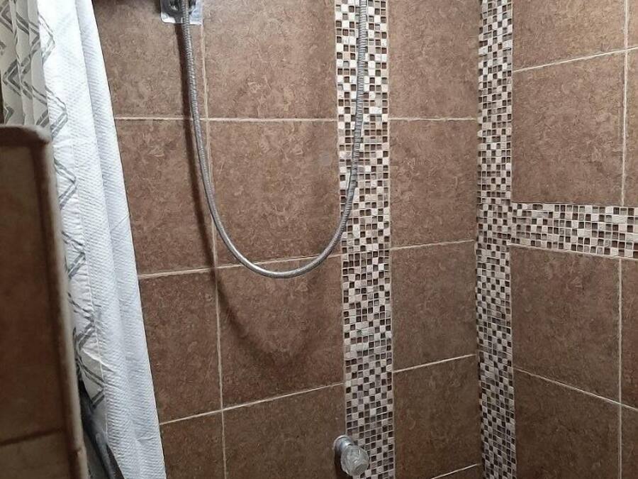 Una ducha con pared de azulejos, cabezal de ducha y cortina.