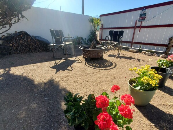 Un patio con un brasero, sillas exteriores y plantas en macetas.
