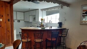 Uma cozinha com ilha central, banquetas e uma janela.