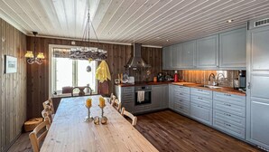 A modern kitchen with grey cabinets, a wooden dining table, and a hanging light fixture. - Amazing home in Sjusjøen with sauna (Sjusjøen)