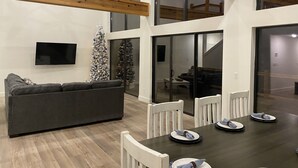 A modern living room with a grey sofa, a dining table set for four, and a Christmas tree. - Lakeview Getaway | 6BR Near Table Rock (Cape Fair)