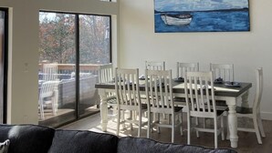 A dining area with a table and chairs, a ceiling fan, and a painting of a boat on water. - Lakeview Getaway | 6BR Near Table Rock (Cape Fair)