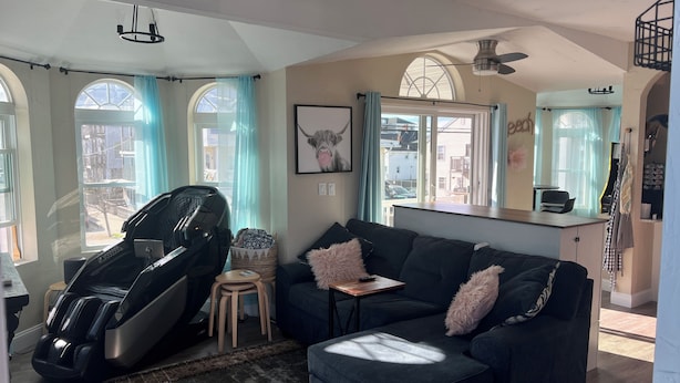 A living room with a massage chair, a dark blue sofa, and a small table. - The Posh Plum - 1 Block to the Casino Ballroom, Bars and Beach (Hampton)