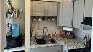 A kitchen with a microwave, sink, and cabinets. - The Posh Plum - 1 Block to the Casino Ballroom, Bars and Beach (Hampton)