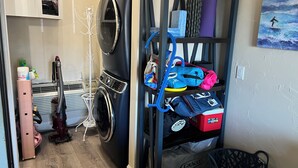 A laundry area with a washing machine, a drying rack, and a shelf with bags and a mat. - The Posh Plum - 1 Block to the Casino Ballroom, Bars and Beach (Hampton)