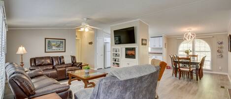 A spacious living room with a fireplace, a dining area, and a kitchen.