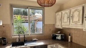 A kitchen with a large window, a dish rack, a microwave, and a sink. - Villa de Luxe, Hyper Centre, Port de Portovecchio (Porto-Vecchio)
