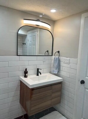 Bathroom features a white sink, mirror, and lighting.
