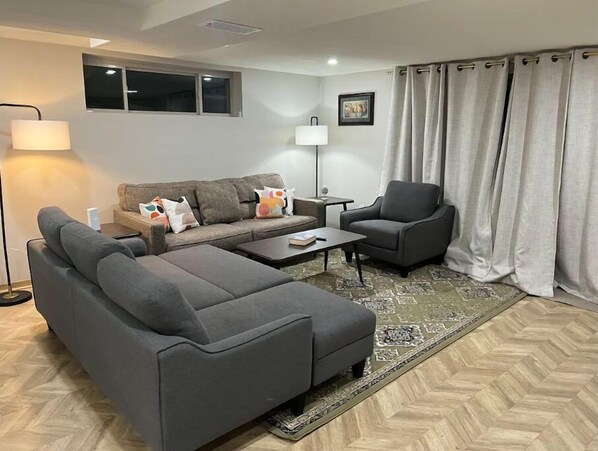 Relax in this stylish living room with a comfortable sofa, coffee table, and armchair, perfect for unwinding with a good book.