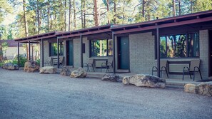 A row of cabins with stone walls and large windows, each with a bench and a door marked with the number 53.