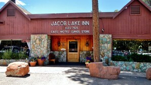 Een gebouw met de naam 'Jacob Lake Inn', met een gevel van steen, een houten ingang en een bord waarop staat dat het een café, motel en winkel is.