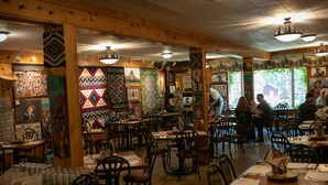Een restaurant met houten inrichting, meerdere tafels en stoelen, en diverse wanddecoraties.