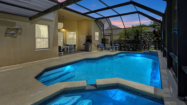 Ein Schwimmbad mit Glasdach, umgeben von Liegestühlen und einer Terrassenfläche.