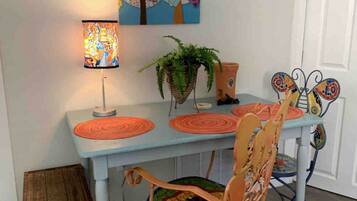 Een eetgedeelte met een tafel, stoelen, een lamp en een schilderij aan de muur.