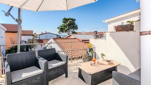 Un patio exterior con mobiliario de mimbre, una mesa y una sombrilla.