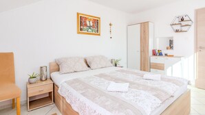Un dormitorio moderno con una cama de madera, mesitas de noche, una silla, una planta pequeña y un cuadro en la pared.