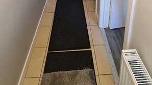 A hallway with a carpeted staircase, a doormat, and a radiator. - Rutland Street Townhouse Belfast (Belfast)