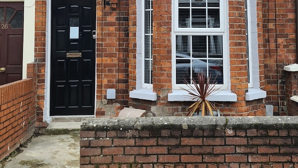 A two-story brick house with a black front door, two windows with white frames, and a small porch area. - Rutland Street Townhouse Belfast (Belfast)