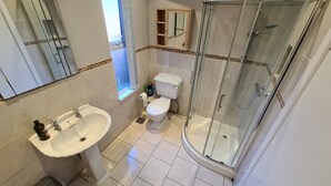 A bathroom with a sink, toilet, and glass-enclosed shower. - Rutland Street Townhouse Belfast (Belfast)