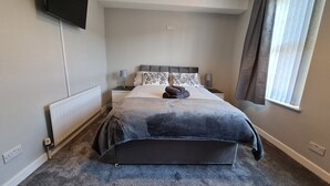 A modern bedroom with a large bed, bedside lamps, a flat-screen TV, and a window with curtains. - Rutland Street Townhouse Belfast (Belfast)