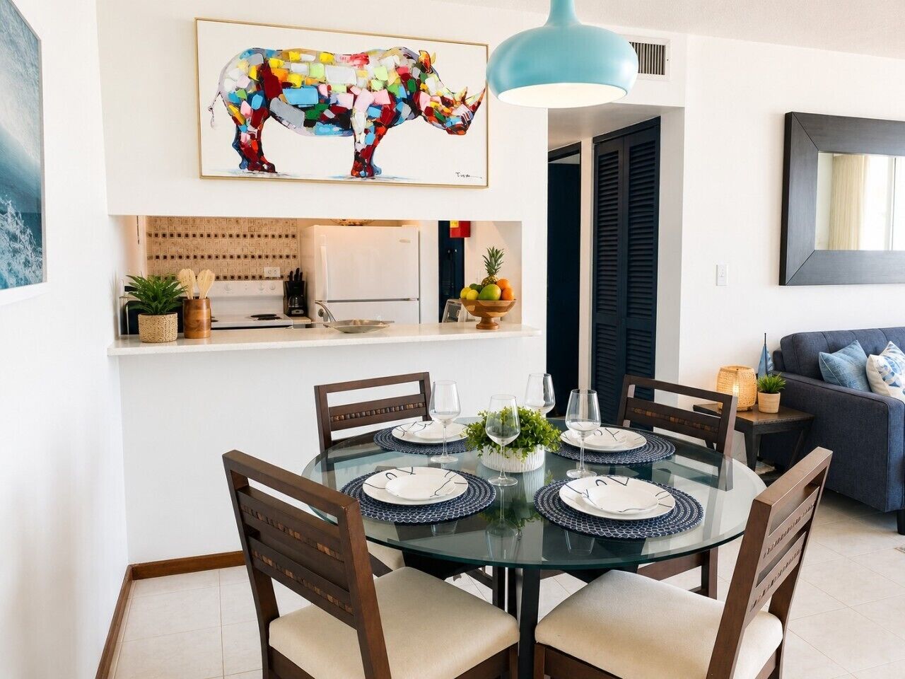 Comedor con mesa de vidrio redonda dispuesta para cuatro personas, rodeada de sillas.