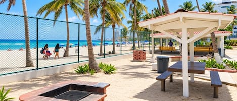 Beachfront recreation area with picnic tables and a BBQ grill.