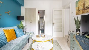 Een woonkamer met een blauwe bank, een ronde salontafel en een televisie op een blauwe kast.