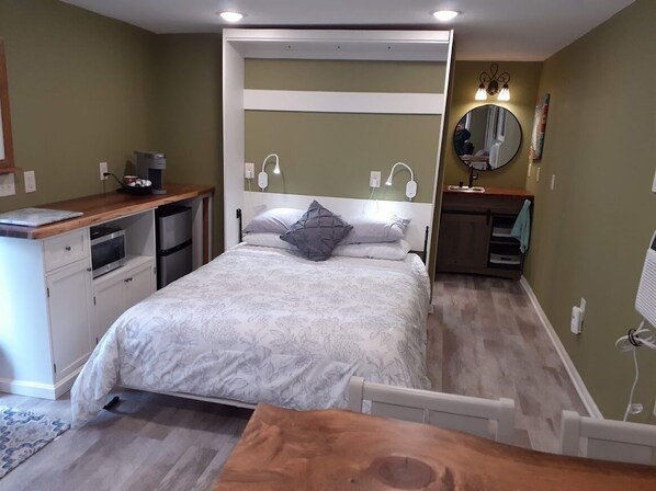 Un dormitorio con cama, mesita de noche y espejo en la pared.