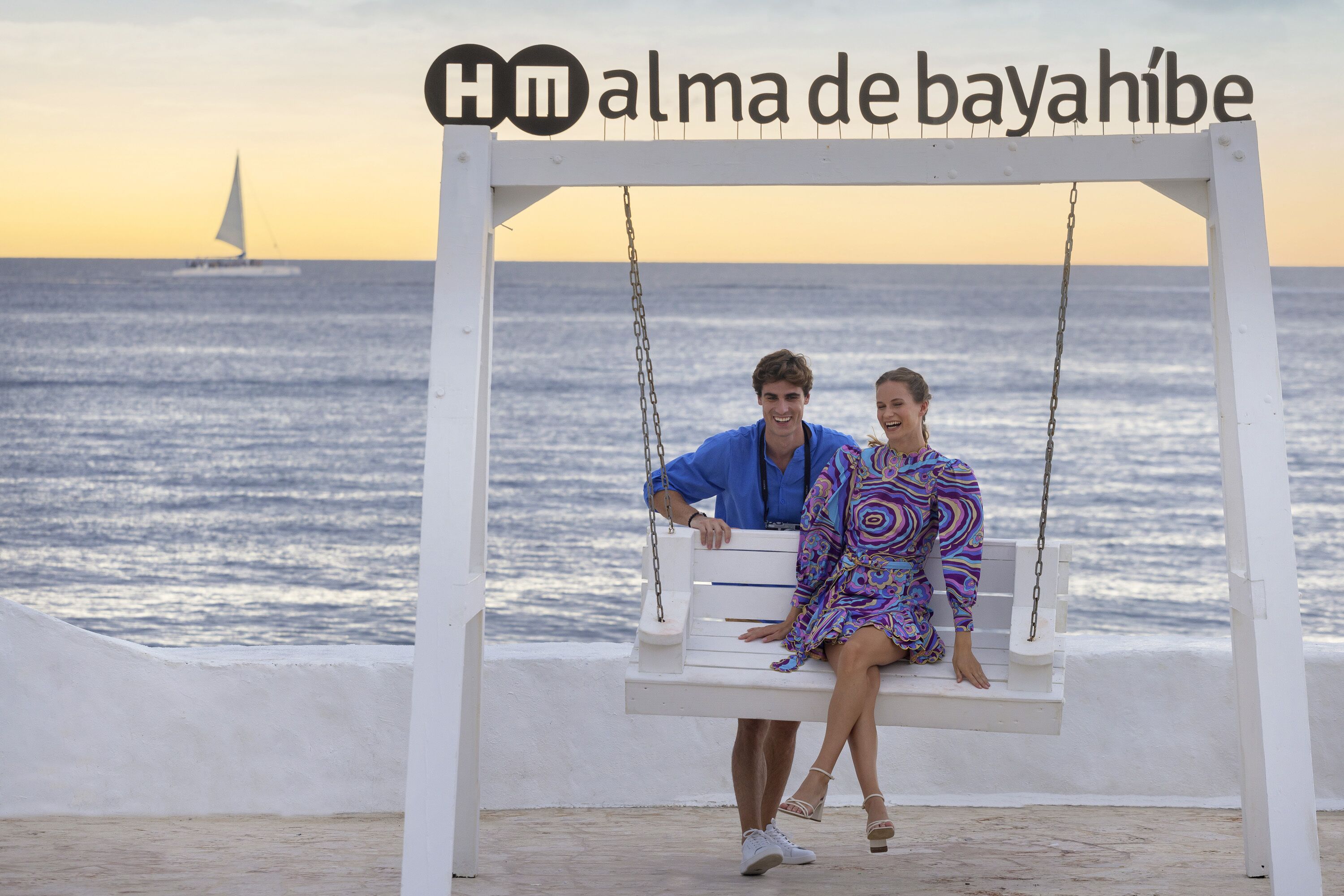 A couple on a swing with a beach and ocean in the background.