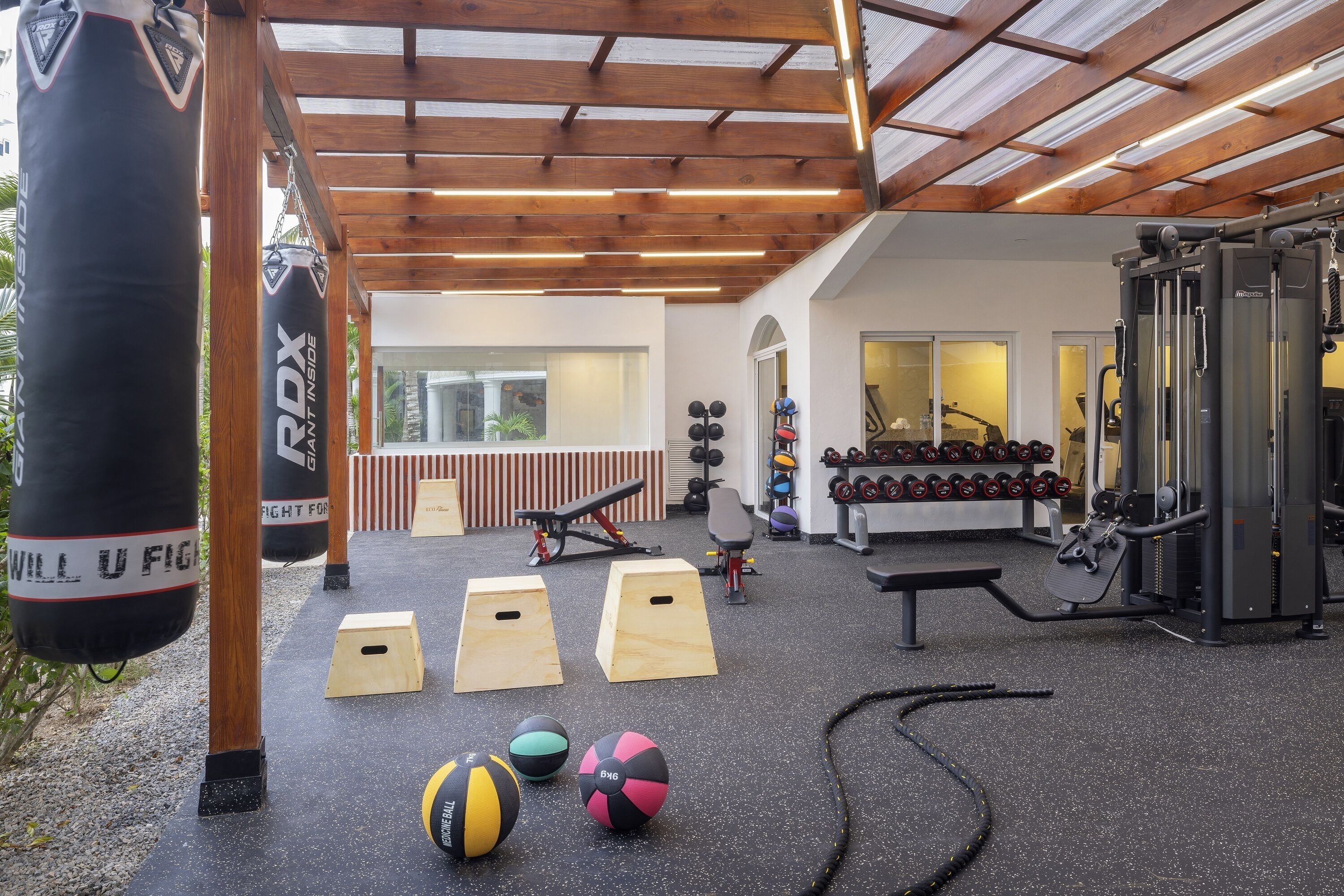 Ein Fitnessstudio mit Trainingsgeräten, Holzbanken und Schlagringen.