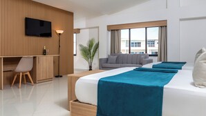 A modern hotel room with a large bed, a desk, a flat-screen TV, and a sofa. - HM Alma de Bayahibe - Adults Only - All Inclusive (San Rafael del Yuma)