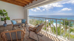 A balcony with wicker furniture, a potted plant, and a view of the ocean. - HM Alma de Bayahibe - Adults Only - All Inclusive (San Rafael del Yuma)