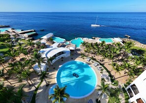 An aerial view of a resort with multiple swimming pools, palm trees, and a view of the ocean. - HM Alma de Bayahibe - Adults Only - All Inclusive (San Rafael del Yuma)