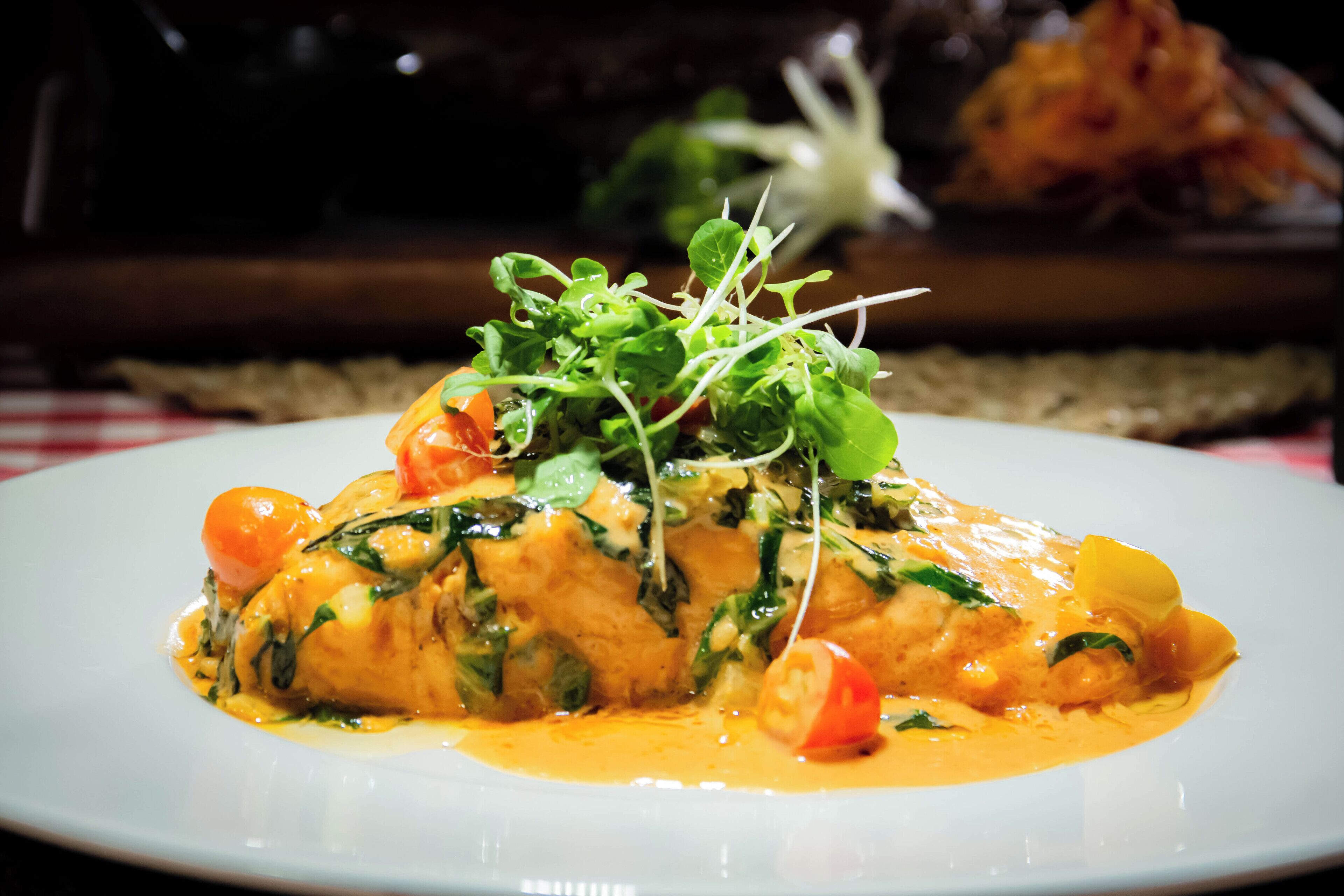 Ein Teller Essen mit cremiger Soße, garniert mit Salat und Tomaten.